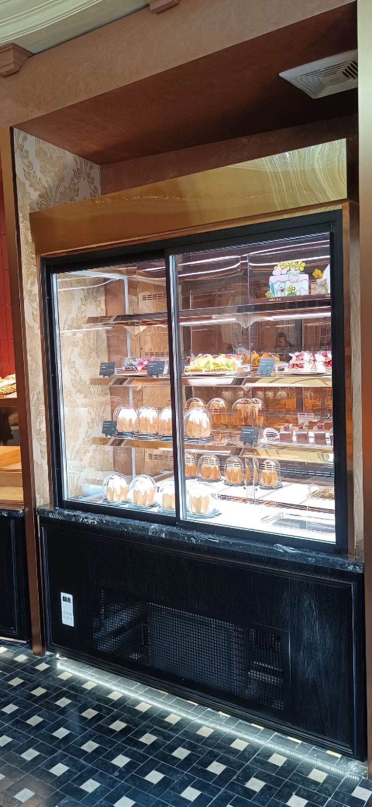 Embedded commercial cake display cabinet with cakes and pastries in a bakery shop